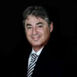 Professional headshot of Brian Praver of Atacama Resources International in black suit against black background